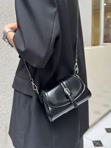 Detail shot of a black patent leather shoulder phone bag with silver metal buckle strap.