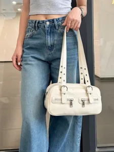 Minimalist white bowling shoulder bag with metal grommets and dual zipper pockets for women.