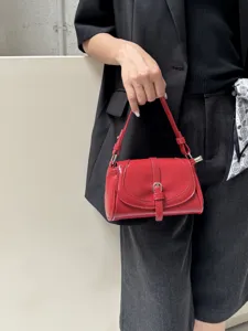 Detail shot of a vintage red patent leather shoulder bag with chic flap and metal buckle.