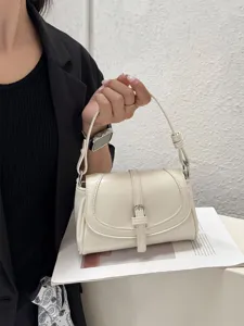 Close-up view of the elegant white patent leather shoulder bag with metal buckle.
