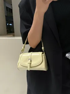 Detail shot of a butter yellow patent leather shoulder bag with buckle, elegant accessory.