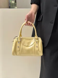 Yellow leather bowling handbag Boston shoulder crossbody bag with metal studs and top handle.