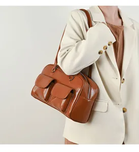 Detail view of the retro brown leather shoulder handbag with dual front pockets and zipper.