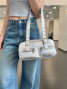 Silver metallic bowling shoulder bag with dual straps and chic front zipper pockets.