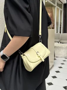 Close-up detail of the retro yellow leather shoulder bag with fine strap and metal buckle.