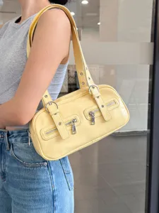 Detail view of stylish yellow leather shoulder bag with double zipper and chic metal buckle.