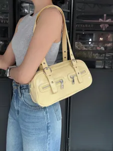 Detailed view of yellow vintage bowling shoulder bag with dual straps and sleek metal hardware.