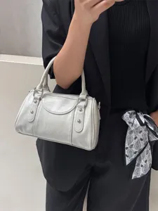 Detail of stylish grey leather bowling handbag with metallic studs and dual top handles.