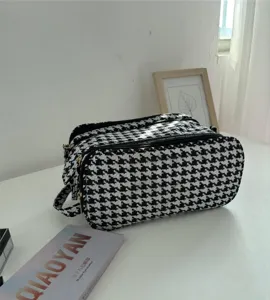 Black and white houndstooth cosmetic bag detail, multi-layer zipper portable travel storage.