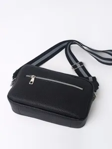 Classic black PU leather crossbody bag detail featuring front zipper pocket and striped strap.