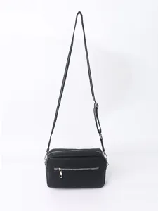 Detail view of the black PU leather crossbody bag, showing texture, zipper, and fine strap.