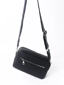 Close up detail of black PU leather crossbody bag, featuring double zippers and front pocket.