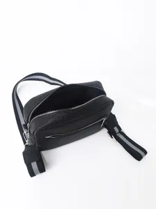 Black PU leather crossbody bag detail, showing zipper pocket and wide striped strap.