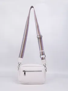 White PU leather crossbody bag detail featuring adjustable striped strap and zipper.