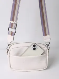 White PU leather crossbody bag with striped strap and front pocket detail showing capacity.