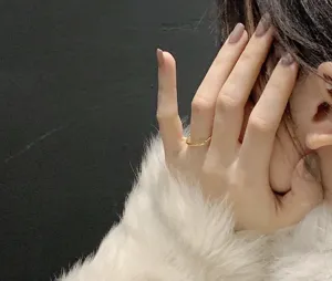 Primo piano di un sottile anello quadrato dorato minimalista, elegante gioiello da donna.