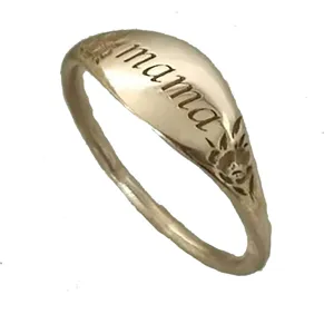 Vista detallada del elegante anillo de sello dorado grabado con mama y patrón floral.