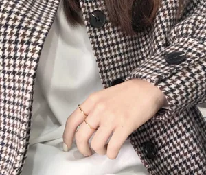 Primo piano di un anello quadrato dorato minimalista indossato alla mano, dettaglio chic.