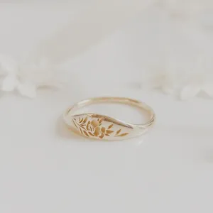 Vue détaillée d'une bague dorée minimaliste gravée de fleurs, design élégant et raffiné.