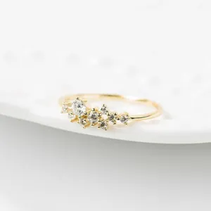 Zarter goldener Cluster-Ring mit funkelnden Zirkonia-Steinen, elegantes geometrisches Detail.