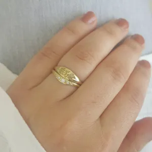 Gros plan de bagues empilées plaquées or 18k avec motif floral gravé et pierres scintillantes.