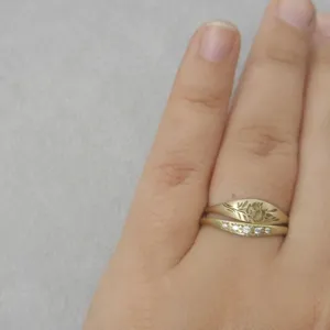 Gros plan de deux bagues empilables plaquees or avec motif floral et strass brillants.