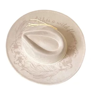 Detail view of the suede western cowboy hat featuring delicate floral and feather prints with text.