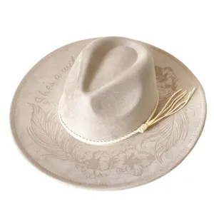 Close-up detail of western cowboy hat featuring floral feather engraving and suede texture.