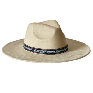 Gros plan sur le détail du chapeau fedora beige à large bord et sa bande ethnique tissée.