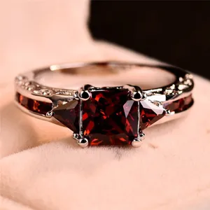 Détail de la bague en zircon rouge luxueuse avec une pierre rouge carrée et une bande argentée.