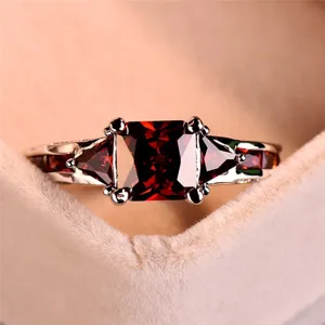 Bague de luxe en zircon rouge avec pierre centrale carree et design de bracelet en metal.