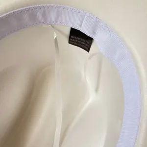 Nahaufnahme der Detailansicht des inneren Futters sowie des Textiletiketts des weißen Hutes.