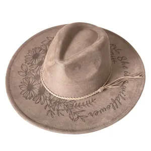 Detailed view of brown suede fedora hat with laser engraved daisy flowers and text.