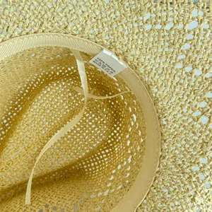 Detailed view of the straw hat interior showcasing the woven paper material quality and brand label.