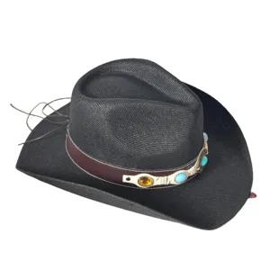 Gros plan sur le détail du chapeau de cowboy en paille noire avec bande de pierres.