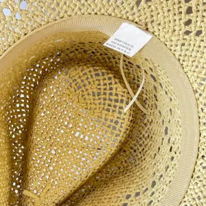 Detailed close-up view of the interior weave and product label of a summer straw sun hat.