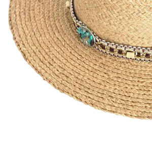 Close-up detail of woven straw hat band with turquoise stones and metallic accents, summer.