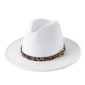 Detalle del sombrero fedora blanco con cinturón de leopardo y hebilla de metal dorado.