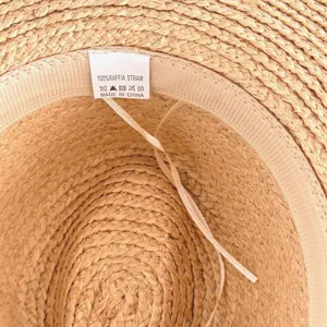 Close up of raffia straw hat interior showing fine woven texture and label detail.