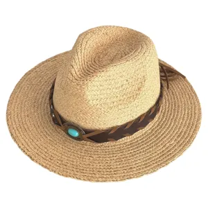Close-up of raffia straw hat with braided leather band and turquoise stone detail.