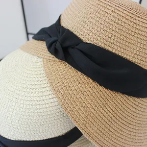 Dettaglio cappello di paglia, texture tessuta, decorazione fiocco nero, spiaggia estiva.