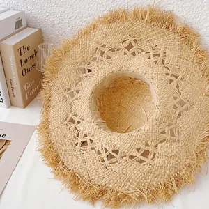 French hollow raffia straw hat with frayed wide brim, summer beach sun protection detail view.