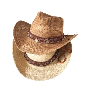 Chapeau de cowboy en paille bohème avec bande à motifs et breloques pour la protection solaire.