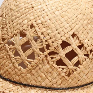 Detail view of woven raffia sun hat texture, breathable hollow cutout design for summer beach travel.