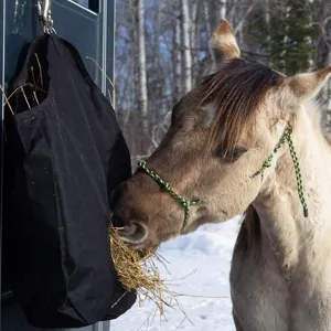 Vista detallada de la bolsa de heno negra duradera para caballos colgada al aire libre.