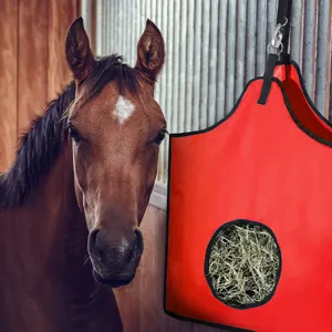 Primer plano detallado de una bolsa de heno roja colgante para caballos en el establo.