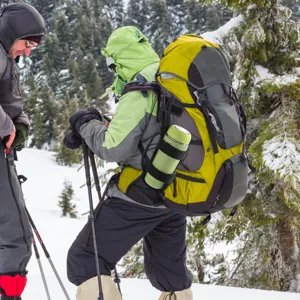 Outdoor hiking backpack with bottle holder and tactical pouch for winter sports and camping gear.