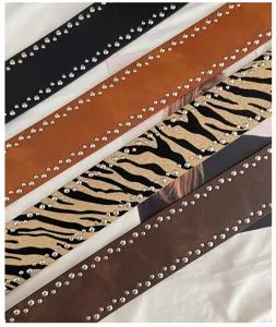 Wide studded belt detail showcasing various colors, textures, and metal rivet decorations.