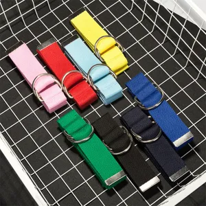 Dettaglio cintura in tela con cinturini multicolore e doppi anelli in metallo disposti ordinati.