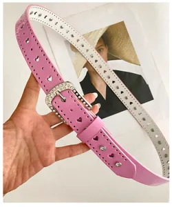 Vue détaillée d'une ceinture en cuir rose avec boucle strass et découpes cœurs mode.